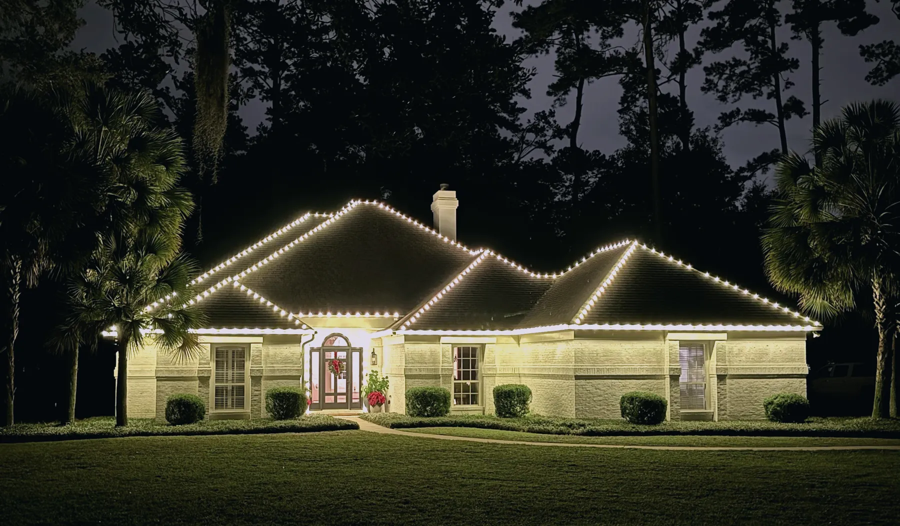 Large Tallahassee estate home lit with warm white Christmas lights on every roof plane
